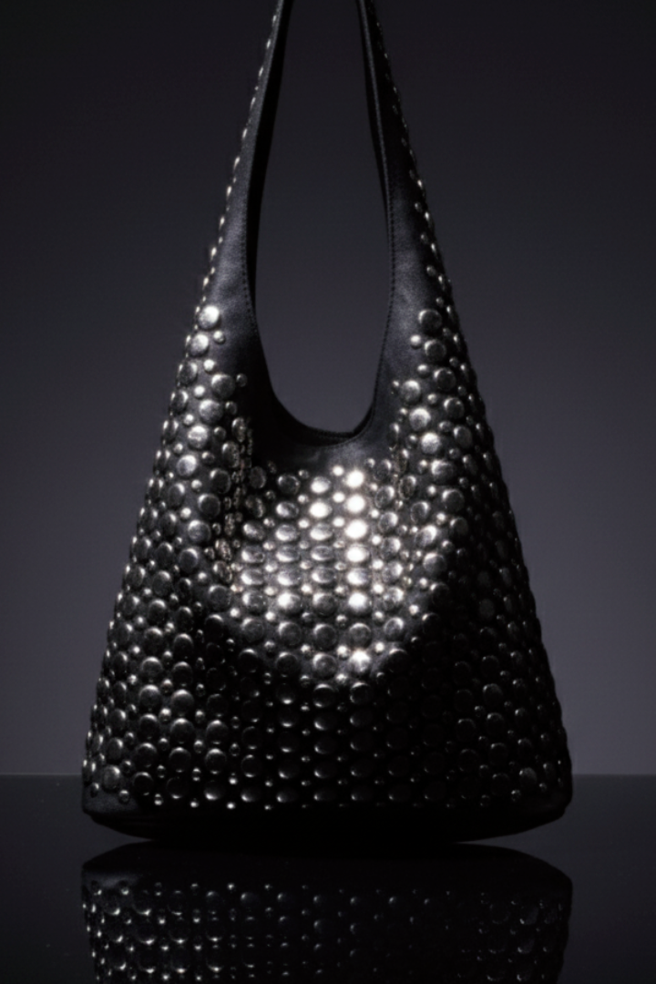 Large black genuine leather shoulder bag with all-over metallic silver studs, displayed on a reflective surface with a dark background.