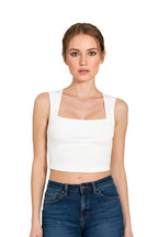 Front view of a woman wearing a white square neck crop top paired with high-waisted blue jeans.