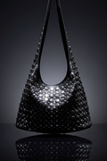 A sleek black genuine leather handbag with round studded detailing, displayed against a dark background, showcasing its elegant and bold design.