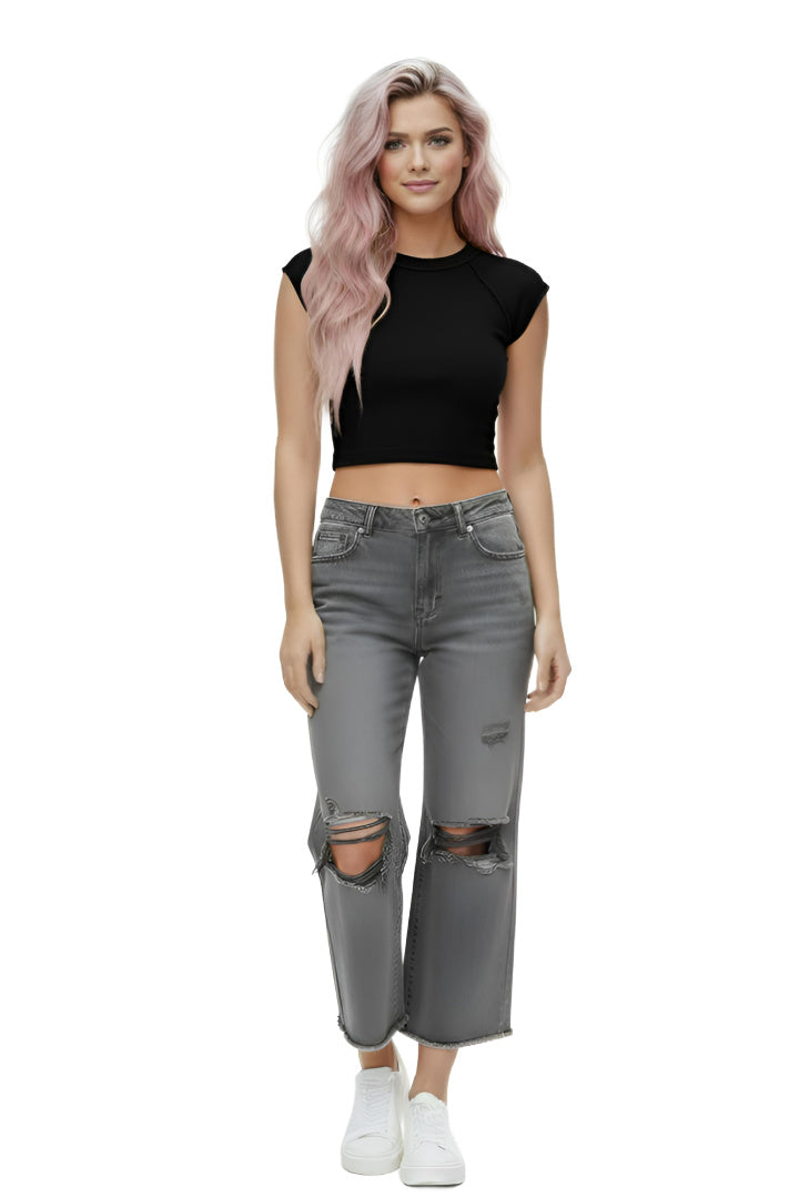 A model wearing a pair of ash-black, high-rise, wide-leg cropped jeans with distressed ripped knees and a frayed raw hem. The model is standing against a white background. Front