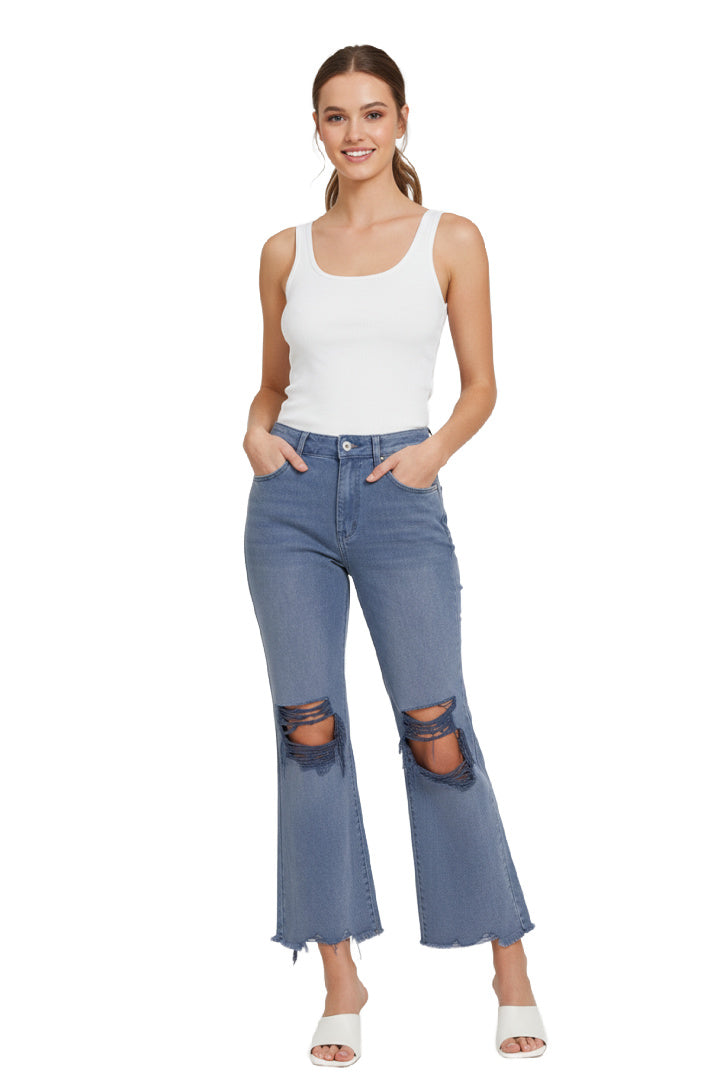 A model wearing a pair of blackberry, high-rise, wide-leg cropped jeans with distressed ripped knees and a frayed raw hem. The model is standing against a white background. Front