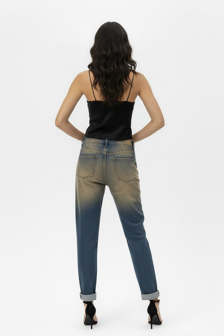 Back full-body shot of a female model wearing vintage oxyde distressed boyfriend jeans with a black satin camisole and black high-heeled sandals, standing against a white background.